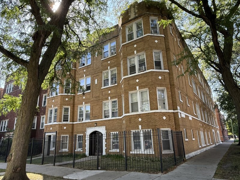 Brick corner apartment building framed by trees